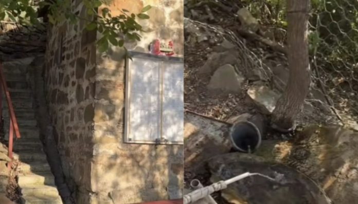 Stone wall with a metal cabinet mounted near a stairwell, red railing along the steps on the left side.